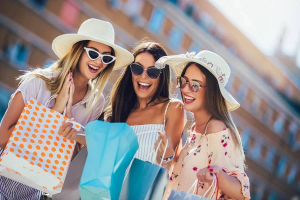 Fröhliche junge Mädchen, die mit Einkaufstüten durch die Straßen gehen. glücklich s — Stockfoto