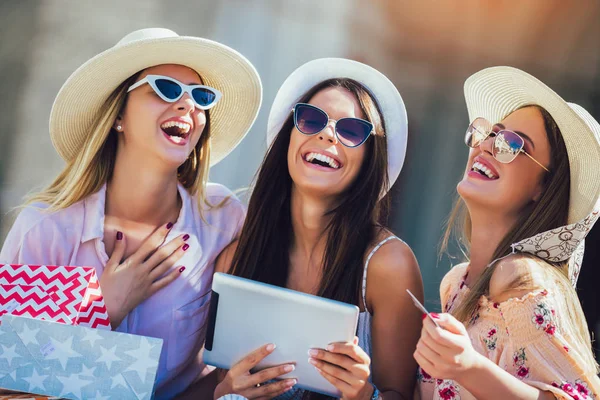 Tři dívky s barevnou nákupní brašny používající digitální tablet a — Stock fotografie