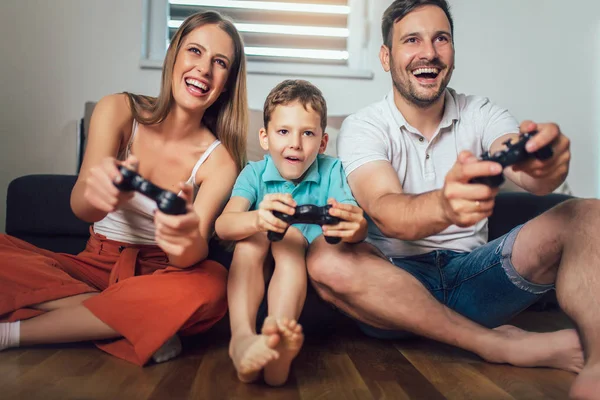 Familia feliz jugando videojuegos en casa y divirtiéndose juntos — Foto de Stock