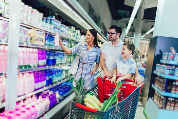 Famiglia felice con bambino e carrello della spesa che compra cibo al supermercato — Foto Stock