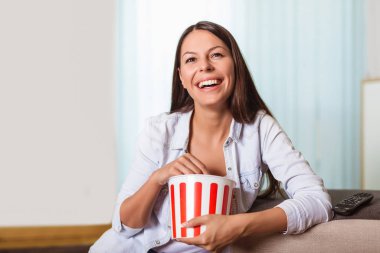 Güzel genç gülümseyen kadın bir film izlerken ve popcor yemek