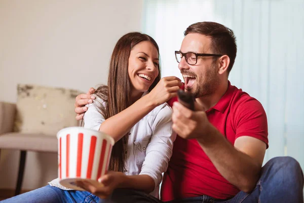 Pareja en el amor sentado en un sofá de la sala de estar, viendo la televisión y ea — Foto de Stock