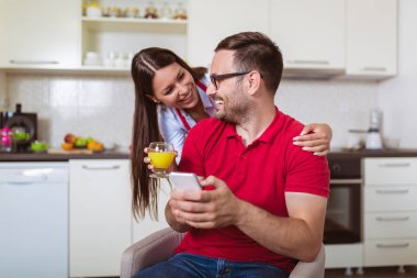 Mutfakta birlikte cep telefonu kullanan çift.