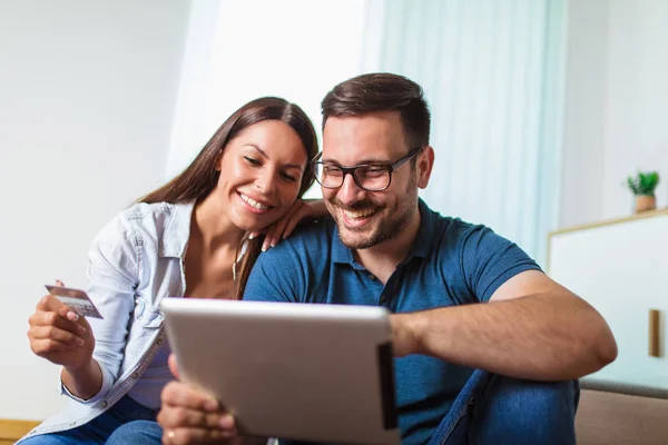 Smiling happy couple with tablet pc computer and credit or bank — Stock Photo, Image