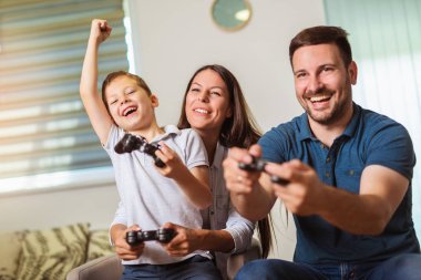 Aile birlikte video oyunları oynarken kanepede oturan gülümseyen