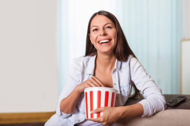 Güzel genç gülümseyen kadın bir film izlerken ve popcor yemek