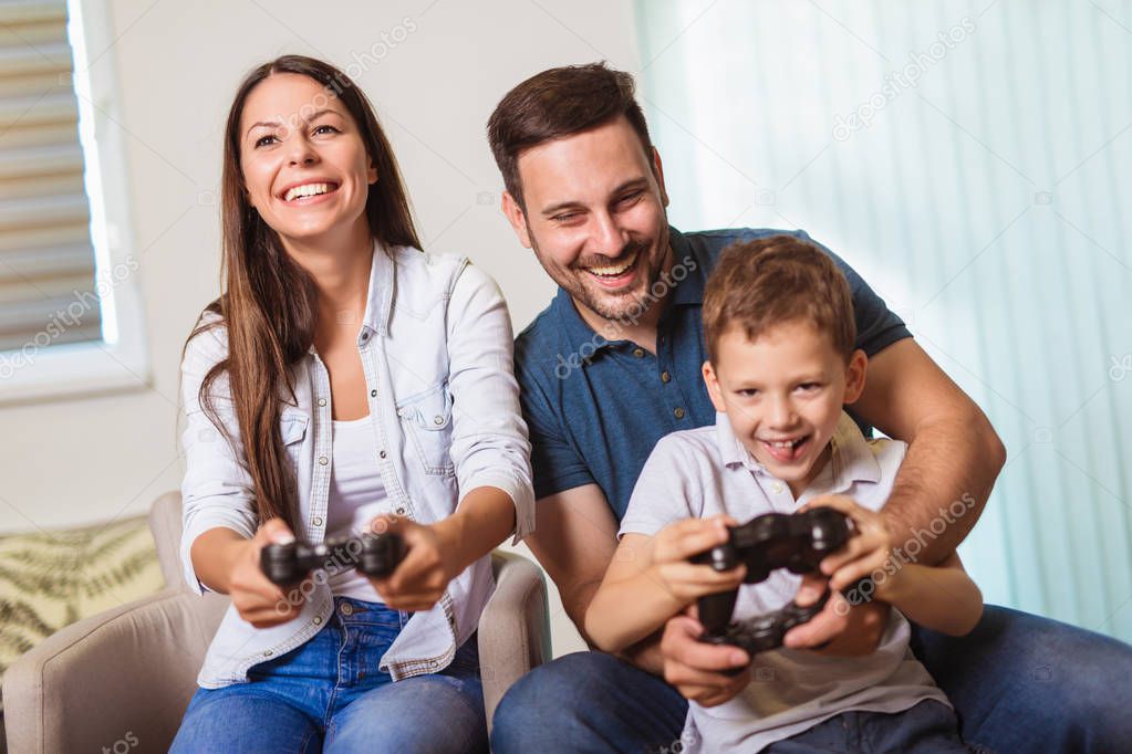 Smiling family sitting on the couch together playing video games