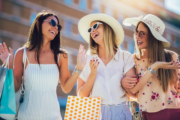 Trzy piękne dziewczyny w okulary przeciwsłoneczne z torby na zakupy w mieście. — Zdjęcie stockowe