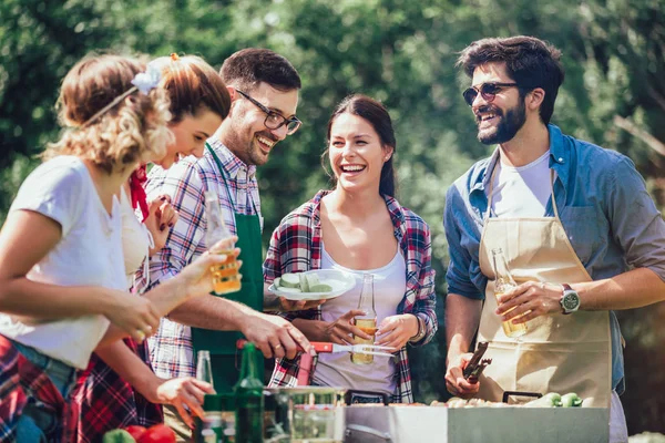 Jovens amigos se divertindo grelhando carne desfrutando de churrasqueira . — Fotografia de Stock