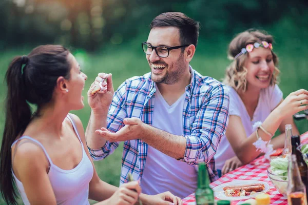 Groep vrienden genieten van een lunchtijd samen in de natuur. — Stockfoto