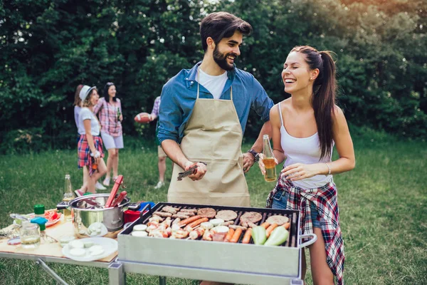 Young friends having fun grilling meat enjoying barbecue party. — Stock Photo, Image