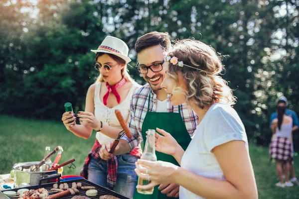 Unge venner har det sjovt grillning kød nyder grill fest . - Stock-foto