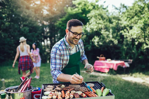 Bonito macho preparando churrasco ao ar livre para amigos — Fotografia de Stock