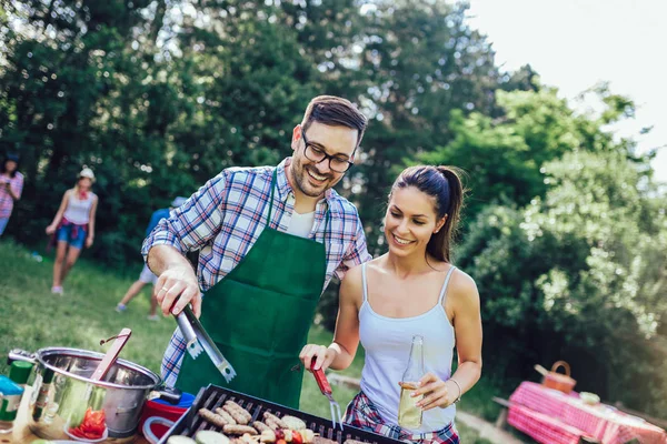 Tineri prieteni având distracție gratar carne se bucură de grătar petrecere . — Fotografie, imagine de stoc