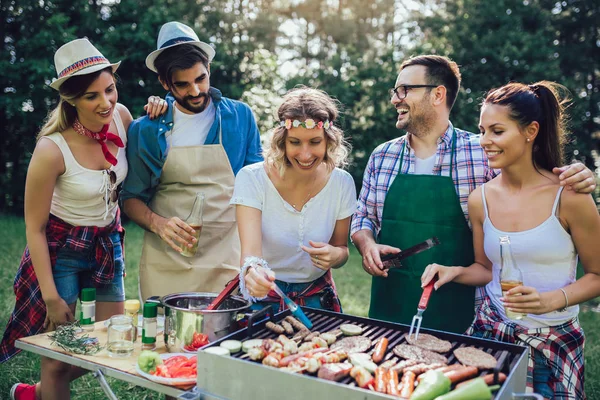 Unge venner har det sjovt grillning kød nyder grill fest . - Stock-foto