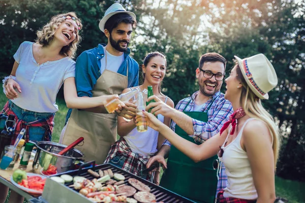 Unge venner har det sjovt grillning kød nyder grill fest . - Stock-foto