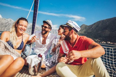 Yelkenli güvertede oturan ve eğlenmek gülümseyen arkadaşlar. Tatil