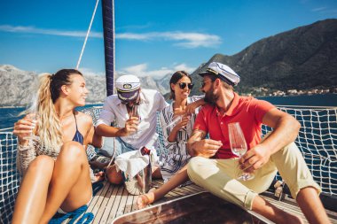 Yelkenli güvertede oturan ve eğlenmek gülümseyen arkadaşlar. Tatil