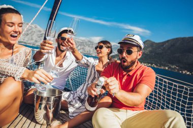 Yelkenli güvertede oturan ve eğlenmek gülümseyen arkadaşlar. Tatil