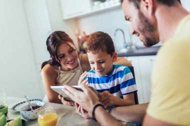Aile mutfak masasında kahvaltı yeme ve dijital masa kullanarak