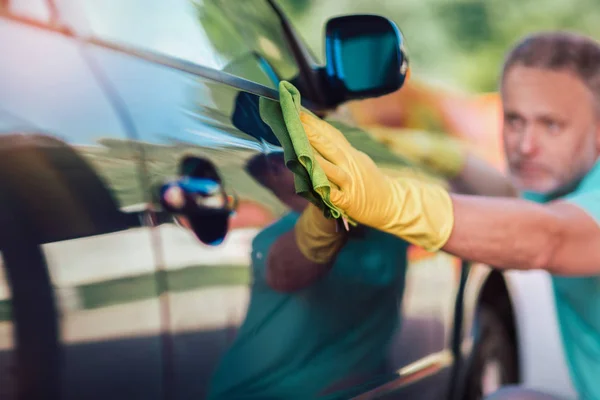 Hombre sosteniendo la microfibra en la mano y pule el coche . — Foto de Stock