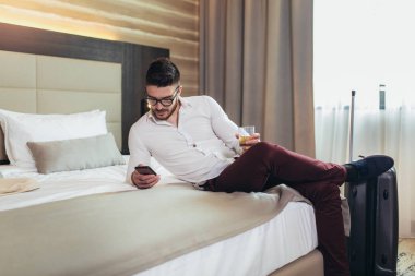 Otel odasında akıllı telefon kullanan genç adam iş seyahati 