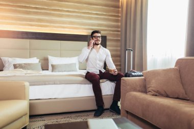 Otel odasında akıllı telefon kullanan genç adam iş seyahati 