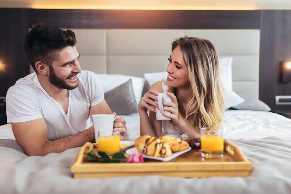 Молодая счастливая пара завтракает в роскошном номере отеля . — стоковое фото