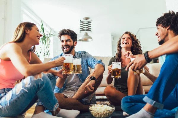 Amigos comiendo palomitas de maíz y bebiendo cerveza taza en casa, divertirse — Foto de Stock