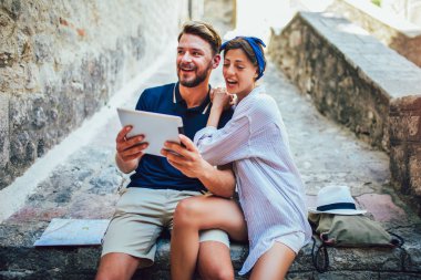 Merdivenlerde dijital tablet kullanan romantik turist çifti.