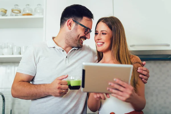 Молодая пара с помощью цифрового планшета на кухне — стоковое фото