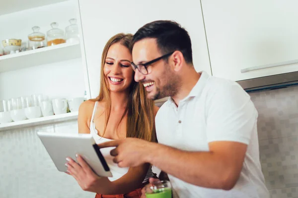Молодая пара с помощью цифрового планшета на кухне — стоковое фото