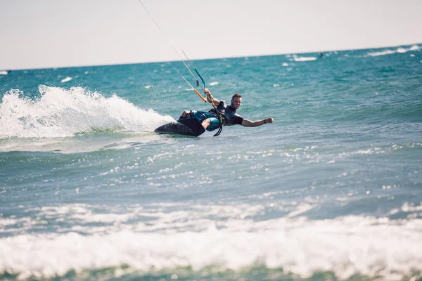 Kitesurfing. Man rides on kite on waves — Stock Photo, Image