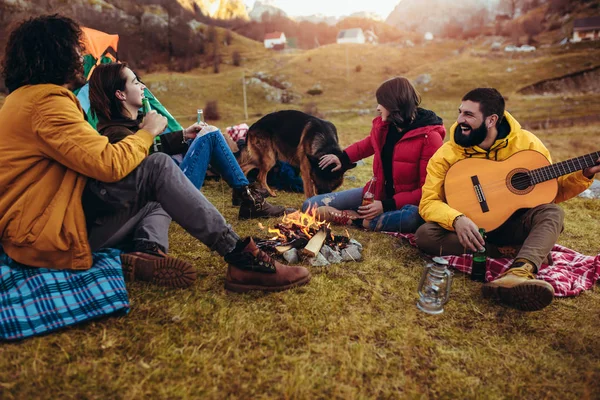 Gruppe lächelnder Freunde am Lagerfeuer im Zelten — Stockfoto