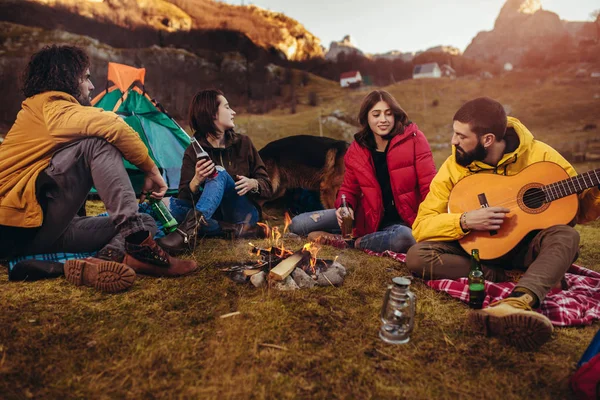 Grup de prieteni zâmbitori care stau în jurul focului de tabără în camping — Fotografie, imagine de stoc