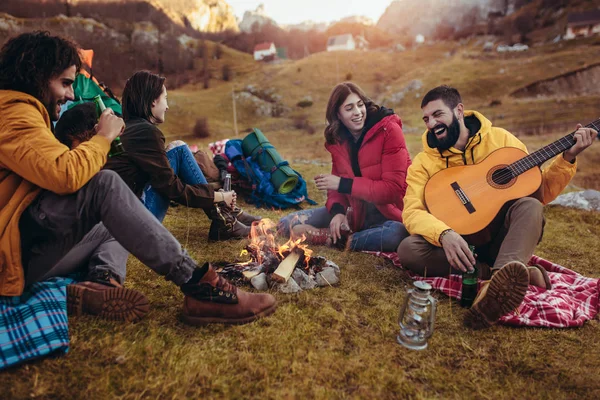 Grup de prieteni zâmbitori care stau în jurul focului de tabără în camping — Fotografie, imagine de stoc