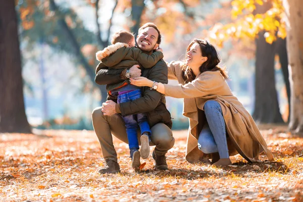 Giovane famiglia si diverte nel parco autunnale con suo figlio . — Foto Stock