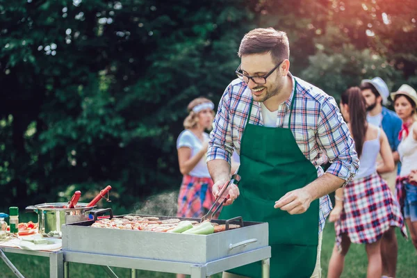 Красивий чоловік готує барбекю на відкритому повітрі для друзів — стокове фото
