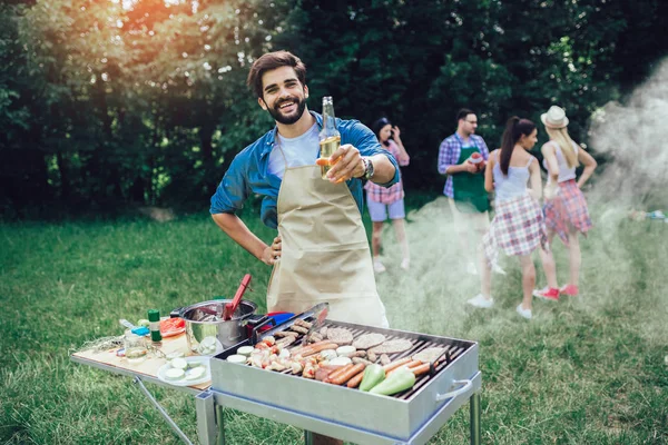 Красивый мужчина готовит барбекю на открытом воздухе для друзей — стоковое фото