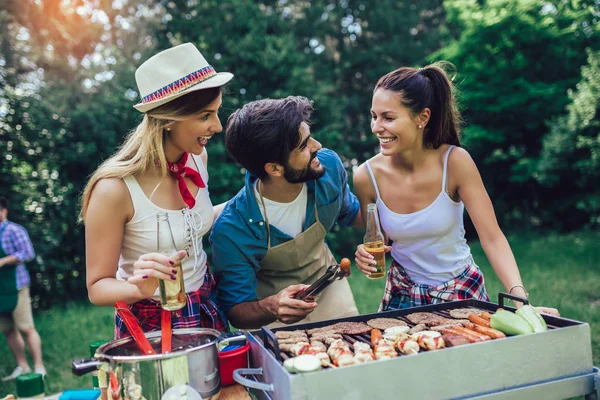 Jóvenes amigos divirtiéndose asando carne disfrutando de la fiesta barbacoa . —  Fotos de Stock