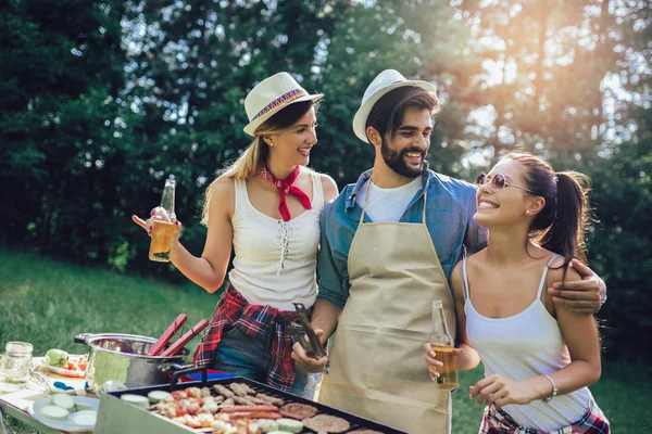 Jóvenes amigos divirtiéndose asando carne disfrutando de la fiesta barbacoa . — Foto de Stock