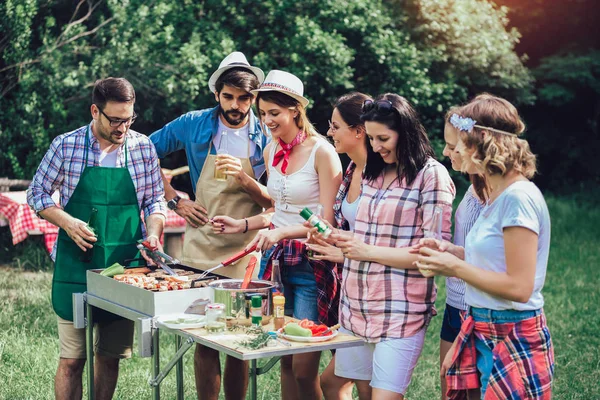 Jovens amigos se divertindo grelhando carne desfrutando de churrasqueira . — Fotografia de Stock