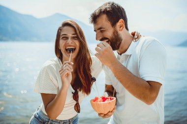 Genç çift arkadaşı ile plajda meyve yeme- yaz partisi