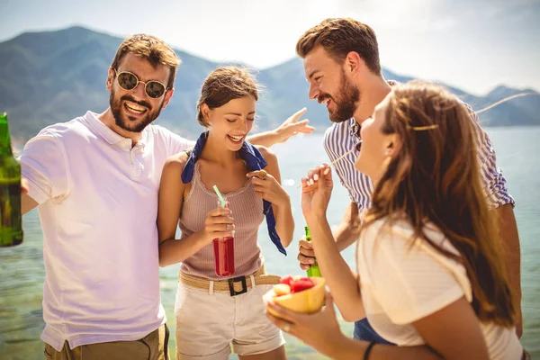 Друзі на пляжі п'ють коктейлі, розважаючись у літній відпустці — стокове фото