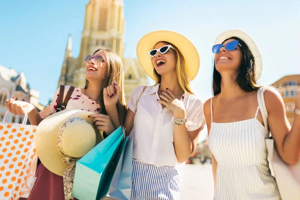 Şehirde alışveriş çantaları ile güneş gözlüğü üç güzel kız. — Stok fotoğraf