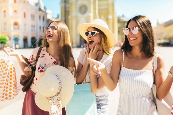 Trois belles filles en lunettes de soleil avec des sacs à provisions en ville . — Photo