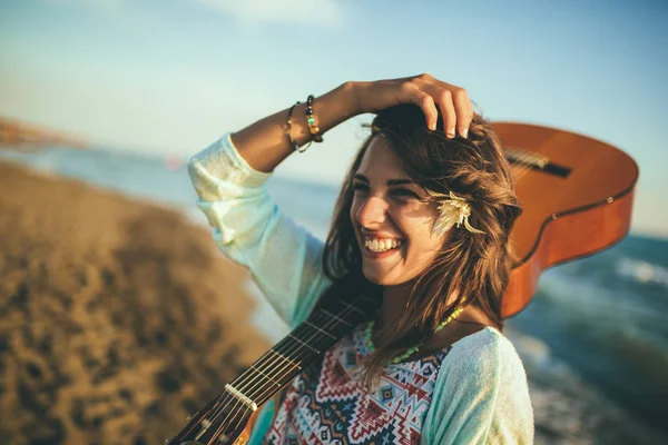 Cute girl walking on the beach holding a guitar in her hands. — Stock Photo, Image