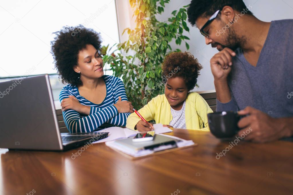 Mother and father helping daughter to do homework learning to ca
