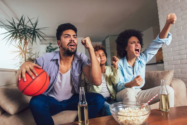 Felice famiglia afroamericana di tre guardare la tv e tifo — Foto Stock