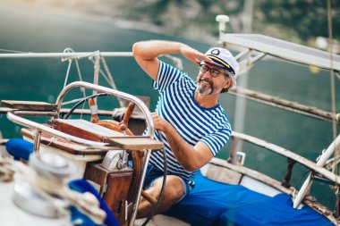 Olgun adam güneşli bir af denizde yelkenli dümen ayakta